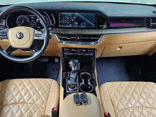 Салон Kia Mohave Masters с коричневыми стёгаными кожаными сиденьями, вид на панель приборов, руль и центральную консоль крупным планом.