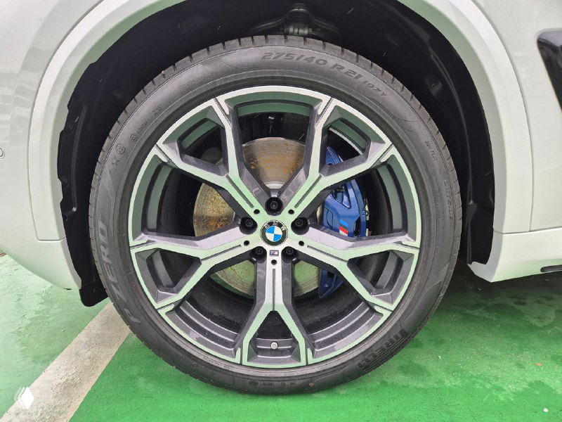 Крупный план колесного диска BMW X5 M Sport с синим суппортом тормоза, чистый диск и современный дизайн легкосплавного колеса.