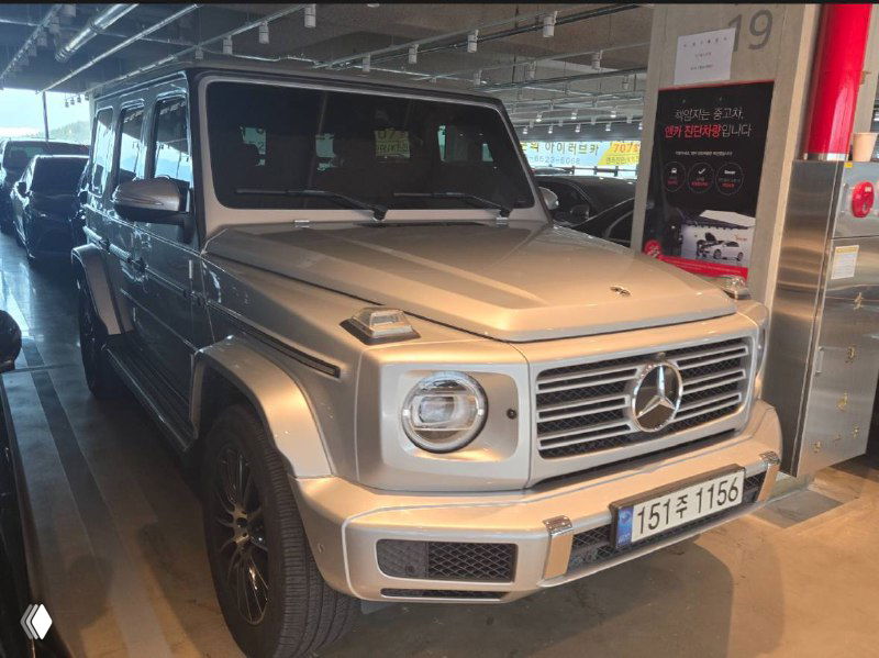 Фронтальный ракурс серебристого Mercedes G‑Class в гараже, хорошо видна решётка радиатора, круглая оптика и капот автомобиля