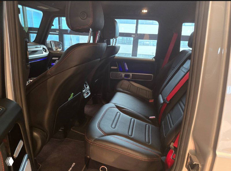 Задний ряд сидений Mercedes G‑Class с чёрной обивкой и красными ремнями безопасности, показан комфорт для пассажиров