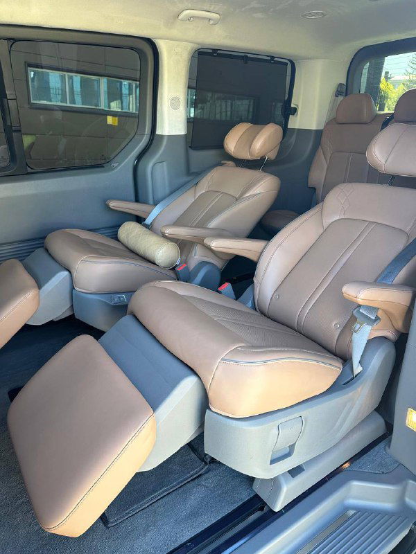 Второй ряд сидений Hyundai Staria: два раскладывающихся коричневых кресла с подставками для ног, видна простора внутри салона.