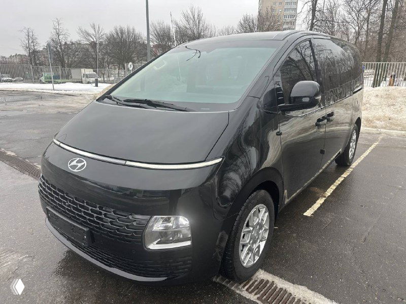 Чёрный Hyundai Staria Cargo показан в трёхчетвертном ракурсе слева спереди; видны колёса, боковая панель и общий силуэт фургона.