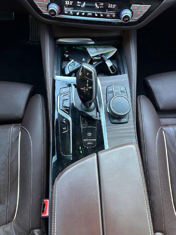 Центральная консоль BMW 540i: рычаг селектора коробки передач, регулятор iDrive и кнопки управления, чистая и ухоженная поверхность.