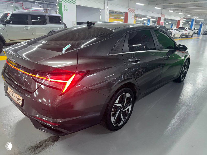 Hyundai Avante в профиль сзади под углом, снимок демонстрирует форму багажника, линии кузова и колёсные диски на парковке.