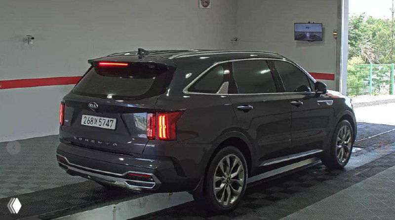 Kia Sorento 2021 вид сзади и под небольшим углом, включены задние фонари, автомобиль на платформе осмотра перед отправкой.
