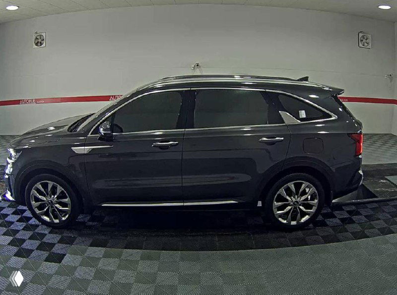 Боковой профиль Kia Sorento 2021, подчёркнута линия кузова и колёсные диски, автомобиль на поверочной решётчатой плитке в боксе.