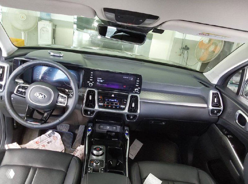 Интерьер Kia Sorento 2021, вид на переднюю панель, рулевое колесо и центральную консоль с включённым экраном мультимедиа.