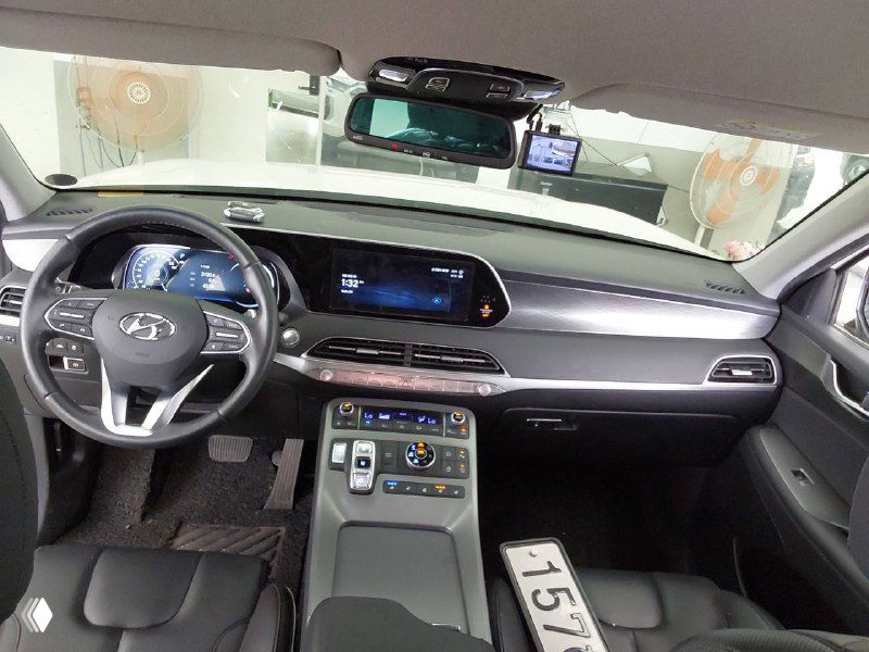 Салон Hyundai Palisade: общий вид торпедо, центральной консоли, руля и передних сидений, показаны материалы отделки и компоновка приборов.