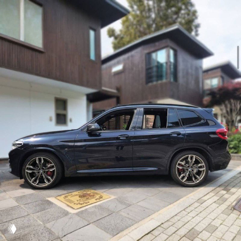 Профиль BMW X3 M40i чёрного цвета: вид сбоку показывает диски, боковую линию кузова и стильные тормозные суппорта в городской среде.