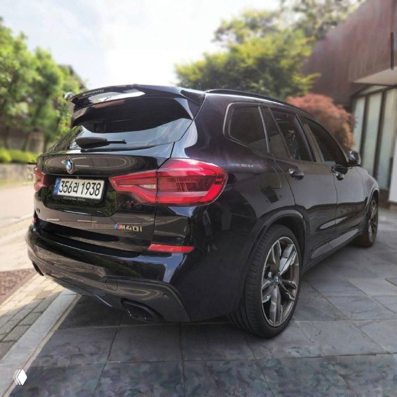 Задняя часть BMW X3 M40i: видны задние фонари, бампер и значок модели на крышке багажника на фоне жилой застройки.