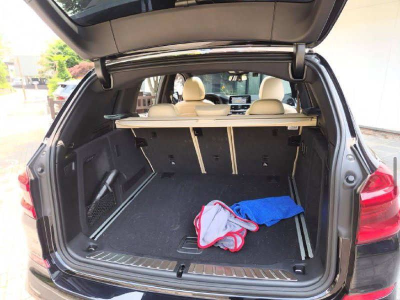 Багажник BMW X3 M40i: открытый объём с полом и креплениями, видны предметы внутри и раскладной механизм задних сидений.