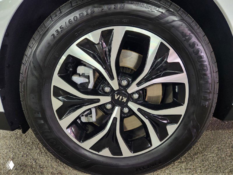 Крупный план легкосплавного диска и шины KIA Carnival, видно рисунок диска и маркировку шины, состояние обода у места продажи.