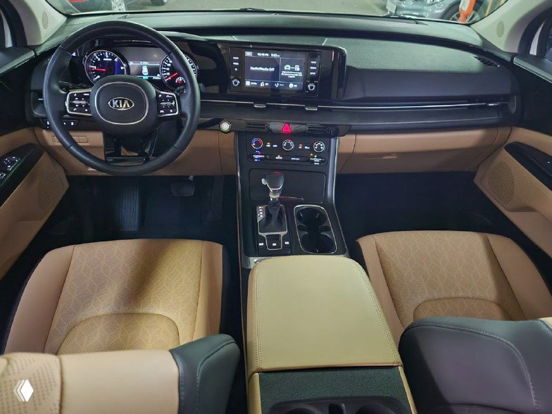Передняя панель и водительское место KIA Carnival: руль с эмблемой Kia, комбинированная приборная панель и центральный экран мультимедиа.