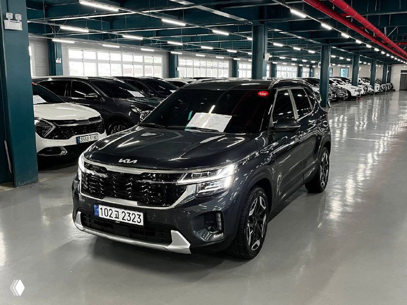 Угловой трёхчетвертной вид серого Kia Seltos Signature 2024 в автосалоне, подчёркнуты линии крыла, решётки радиатора и легкосплавные диски.