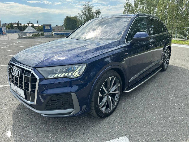 Передняя часть Audi Q7 с крупным планом оптики и защитной решётки; видны стильные светодиодные элементы и хромированные детали.