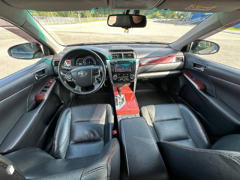 Фото салона Toyota Camry V50: передняя панель, руль, центральная консоль и черные кожаные сиденья, аккуратное состояние интерьера.