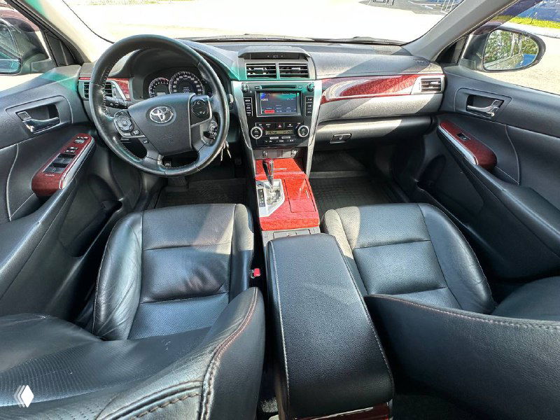 Ещё один общий вид передней части салона Toyota Camry — руль, панель приборов и центральная консоль с декоративными вставками.