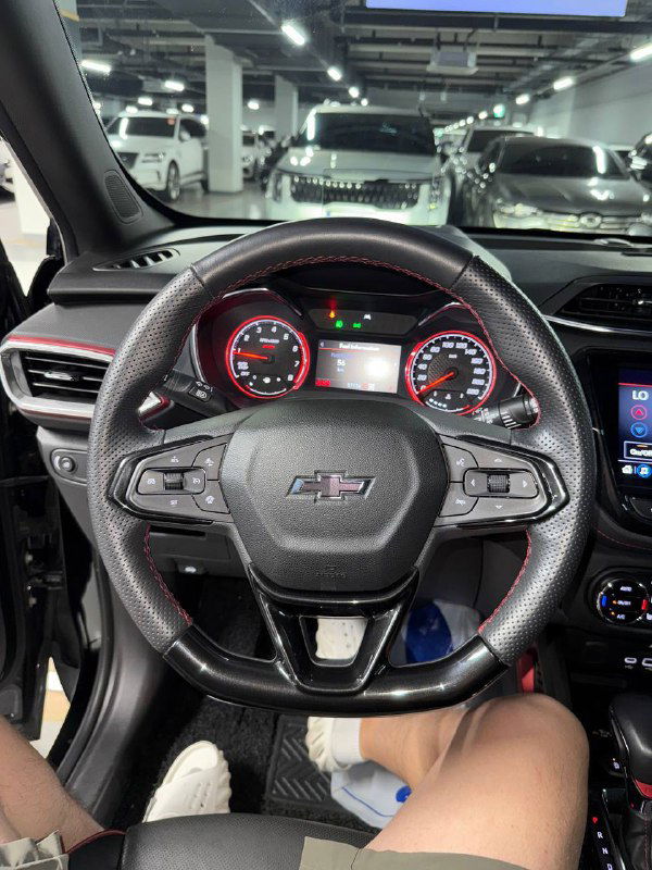 Фото руля и приборной панели Chevrolet Trailblazer: видны кожаный руль с швами, аналоговые стрелочные приборы и часть центрального дисплея.