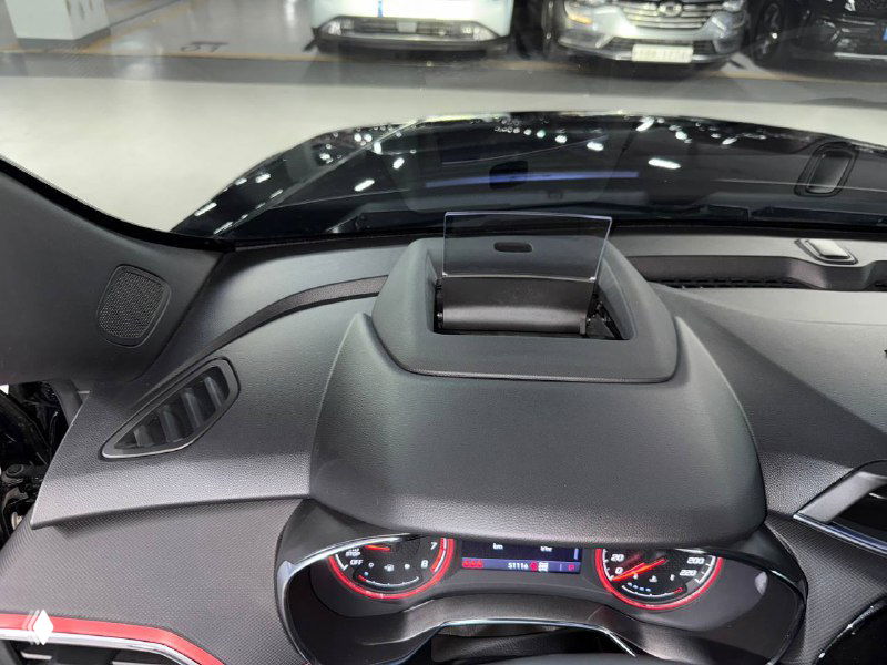 Вид на верхнюю часть приборной панели и козырёк спереди в Chevrolet Trailblazer: видно рельеф торпедо и обзор через лобовое стекло в паркинге.