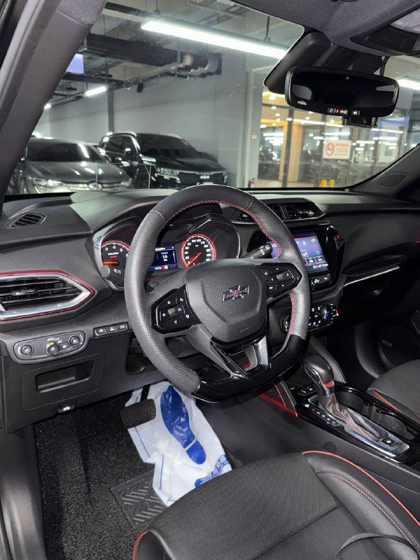 Водительская сторона салона Chevrolet Trailblazer: видны руль, мультимедиа, селектор КПП и элементы отделки с контрастной прострочкой.