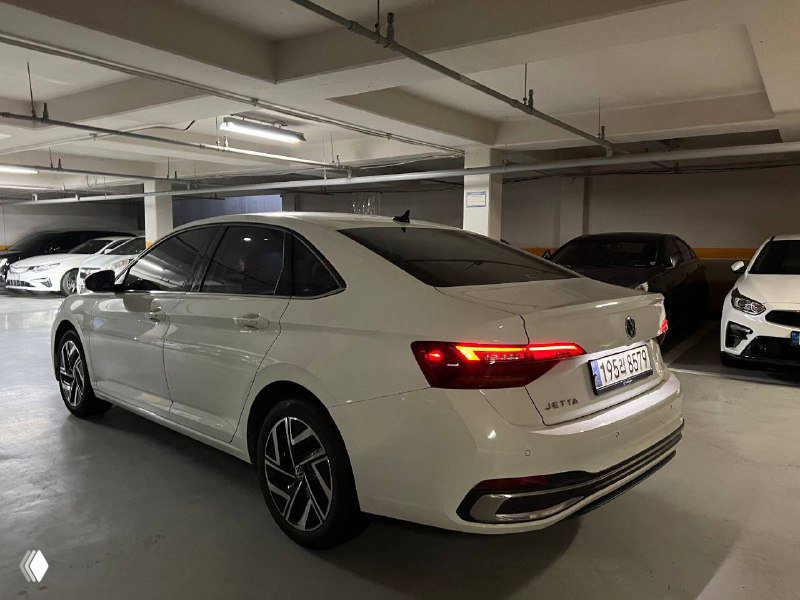 Задне‑боковой вид Volkswagen Jetta: включённые фонари, форма багажника и общая посадка автомобиля на стоянке.