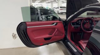 Открытая дверь и красная кожаная отделка салона Porsche: панель двери, поручень, красное сиденье и рулевое колесо — детали интерьера для обзора.