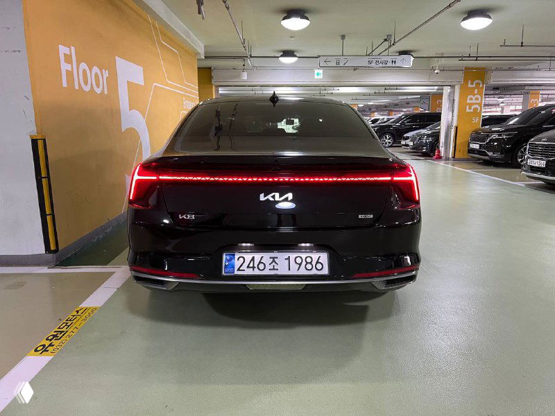 Прямой вид сзади чёрного Kia K8 Signature в паркинге — видна светодиодная задняя оптика и номер автомобиля