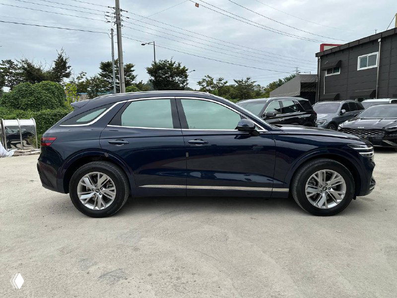 Боковой профиль Genesis GV70 2021 на стоянке: чёткий силуэт кроссовера, видна линия крыши, дверные ручки и колёсные арки.