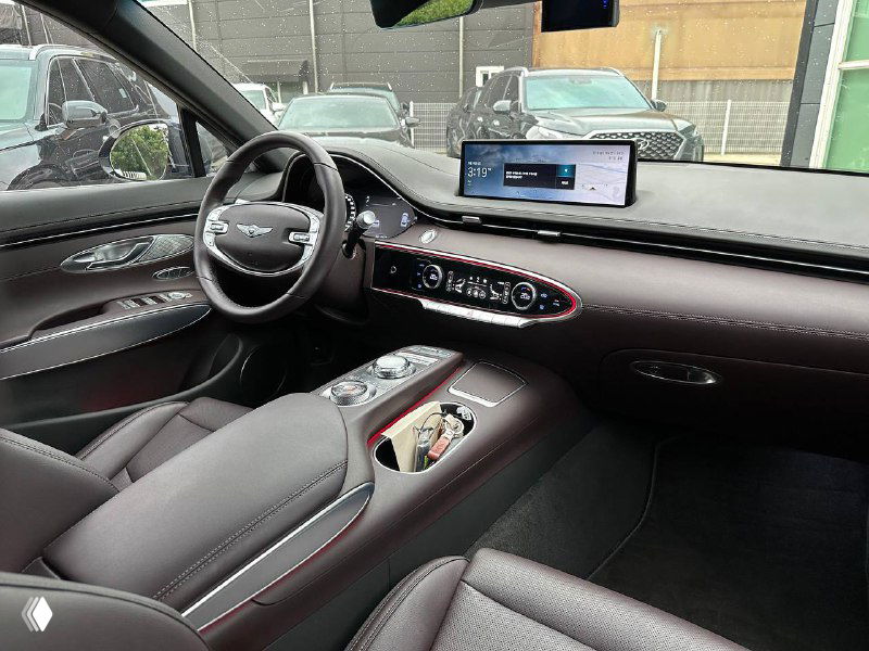 Интерьер Genesis GV70: вид на панель приборов, руль и центральный дисплей с элементами отделки и кнопками управления.