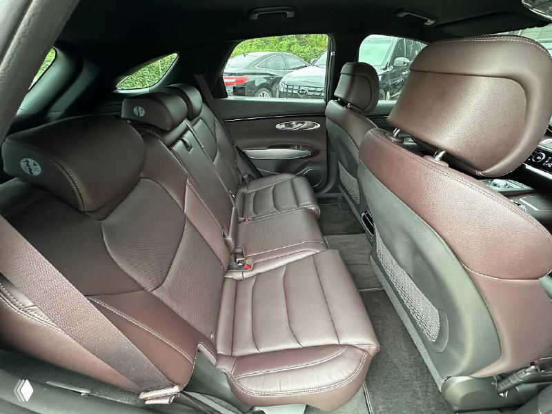 Задний ряд сидений Genesis GV70: трёхместный диван, кожаная обивка и комфортная посадка для пассажиров с подголовниками.