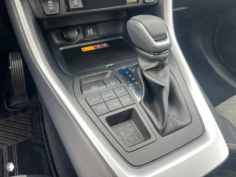 Крупный план панели управления у селектора передач Toyota RAV4: кнопки управления приводом, селектор и отделения для мелочей.
