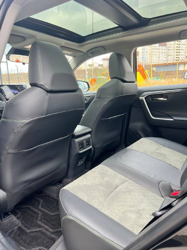 Вид заднего ряда салона RAV4 с панорамной крышей: задние сиденья, обшивка и обзор вверх через панораму.