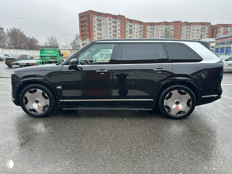 Боковой профиль Zeekr 9X — чёрный кузов, большие зеркальные диски и удлинённый кузов на мокром асфальте