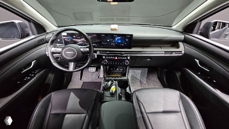 Салон Hyundai Tucson: вид на панель приборов, руль и центральную консоль с мультимедийным экраном и тёмной отделкой интерьера.