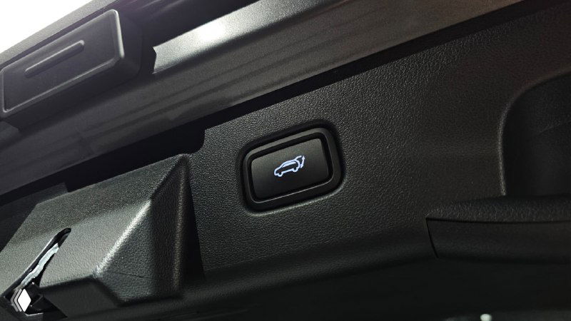 Кнопка автоматического открытия багажника на внутренней кромке крышки багажника Hyundai Tucson — вид крупным планом на механизм.