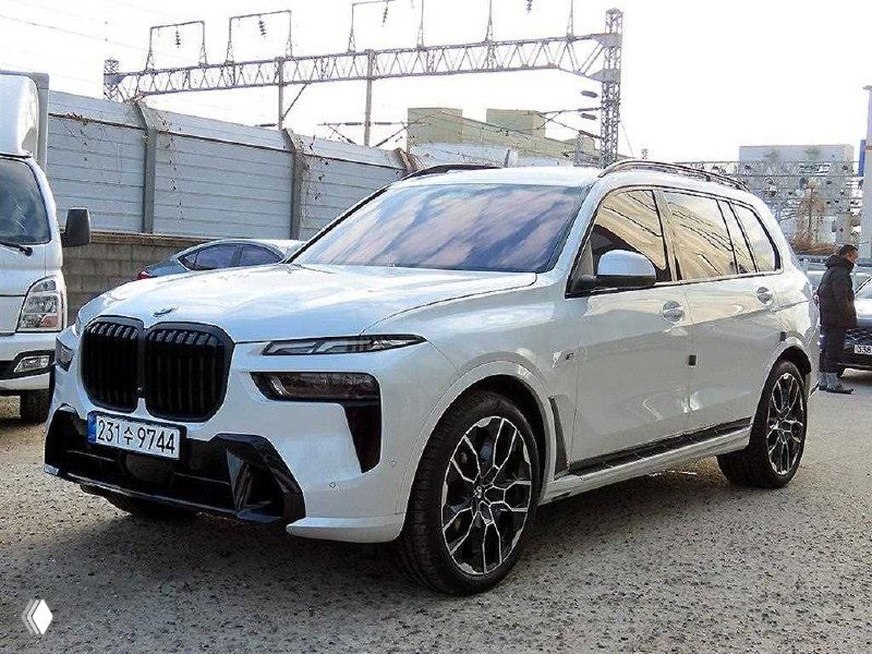 Белый BMW X7 крупным планом в три четверти: боковой профиль, колёса и линии кузова на фоне железнодорожного хозяйства