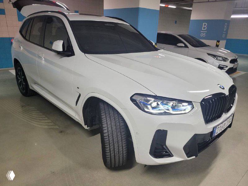 Белый BMW X3 xDrive 20i MSport 2024 года, боковой ракурс, автомобиль повернут в сторону, видны передние колёса и профиль кузова.