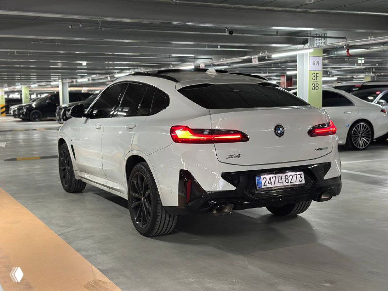 Угловой ракурс задней части BMW X4, показаны пропорции кузова, чёрные колёсные арки и контраст белого кузова с чёрными элементами.