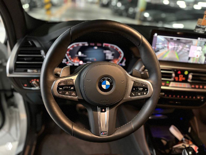 Руль и центральная консоль BMW X4: спортивный руль M‑серии, мультируль с кнопками и часть центрального дисплея мультимедиа.