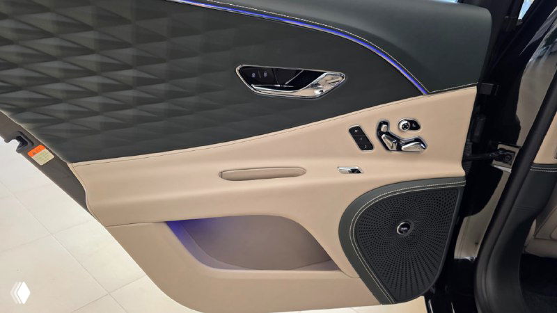 Деталь дверной панели Bentley: комбинированная кожаная отделка, элементы управления сиденьями, динамик и декоративная прострочка с подсветкой в салоне.