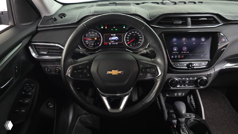 Крупный план рулевого колеса и приборной панели Chevrolet Trailblazer: цифровые индикаторы, отображение скоростей и мультимедийный экран на фоне руля.