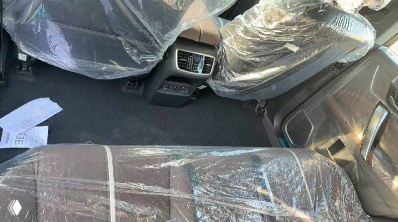 Салон Honda UR-V: задний ряд сидений и центральная консоль, сиденья в защитной плёнке, видны воздуховоды и элементы отделки интерьера.