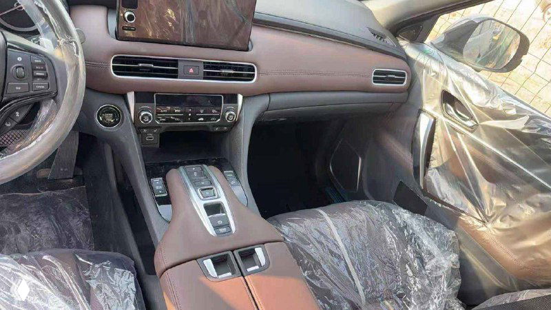 Центральная консоль и передние сиденья Honda UR-V: коричневая отделка, селектор передач и подлокотник, элементы интерьера в защитной плёнке.