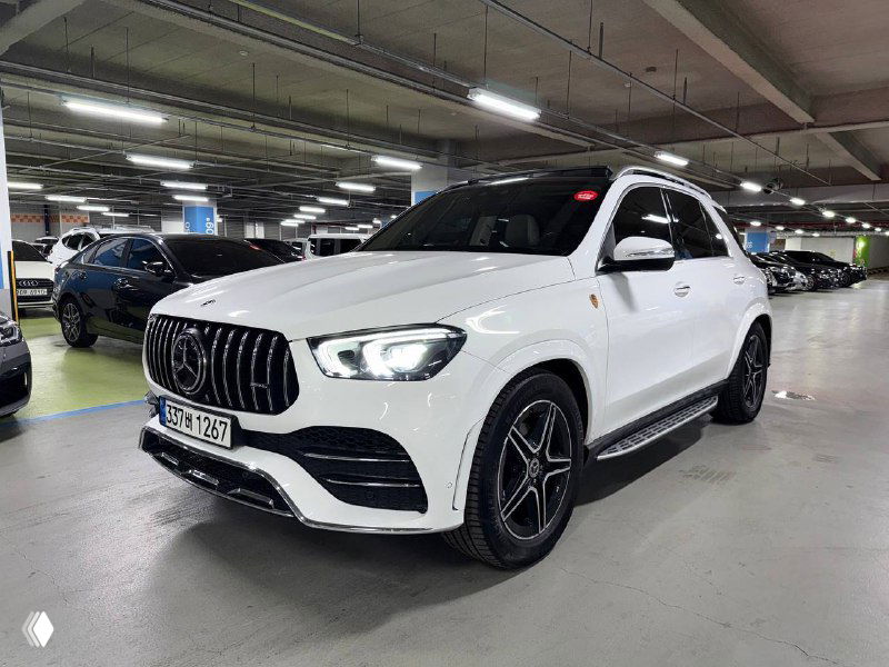 Уголовой вид белого Mercedes GLE 300D в подземном паркинге: профиль, диски и передняя часть кузова на фоне других автомобилей.