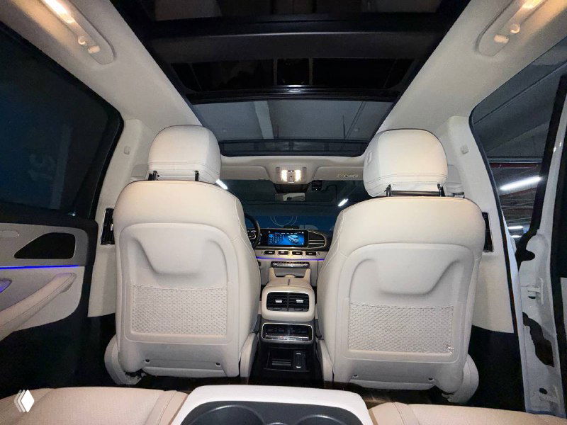 Вид сзади на сиденья и центральную консоль Mercedes GLE 300D: светлая обивка салона, подлокотник и экран в задней части для пассажиров.