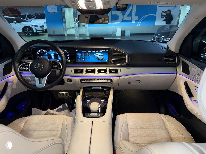 Панорамный вид на переднюю панель и приборную панель Mercedes GLE 300D: большой экран, панорамная подсветка и руль с элементами управления.