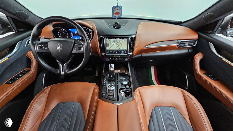 Интерьер Maserati Levante: передняя панель, комбинированная обивка, руль с логотипом Maserati и мультимедиа-экран в центре.