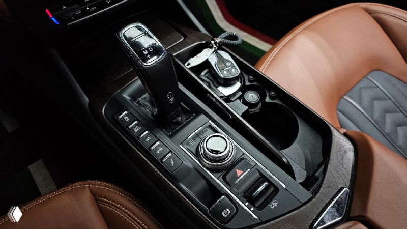 Рядом видна центральная консоль Maserati Levante: селектор коробки, регуляторы и декоративные элементы между сидениями.