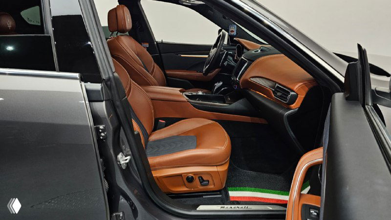 Вид на передние сиденья Maserati Levante с акцентом на элегантную коричневую кожаную отделку и пространство для пассажира.