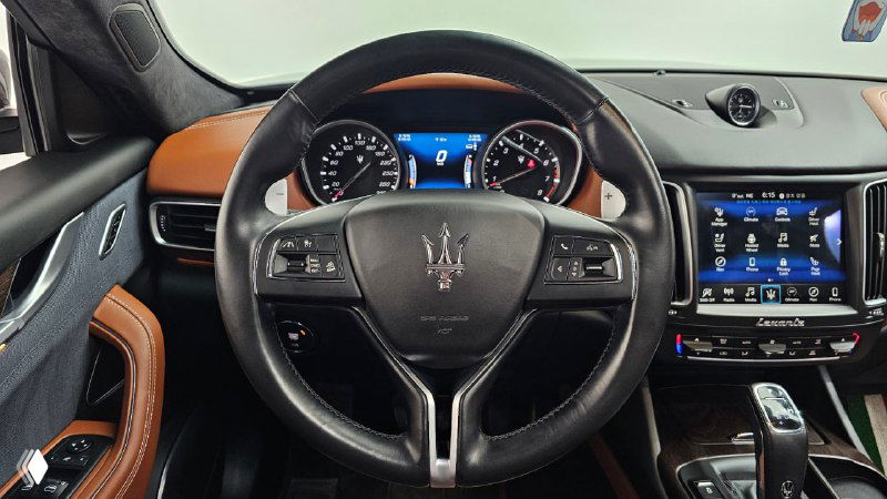 Руль Maserati с логотипом тризубца, панель приборов и мультимедийная панель на центральной консоли в реальном ракурсе.